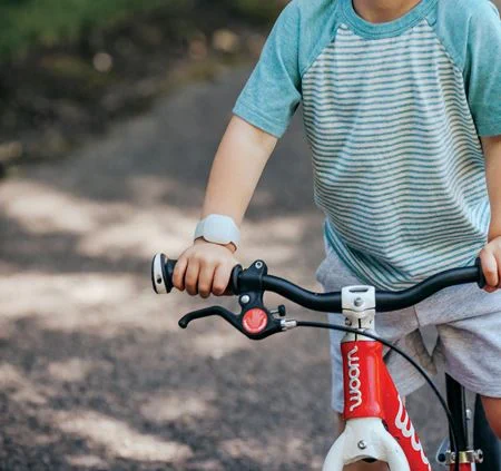 a child on a bicycle with the Littlebird CareTracker on the arm