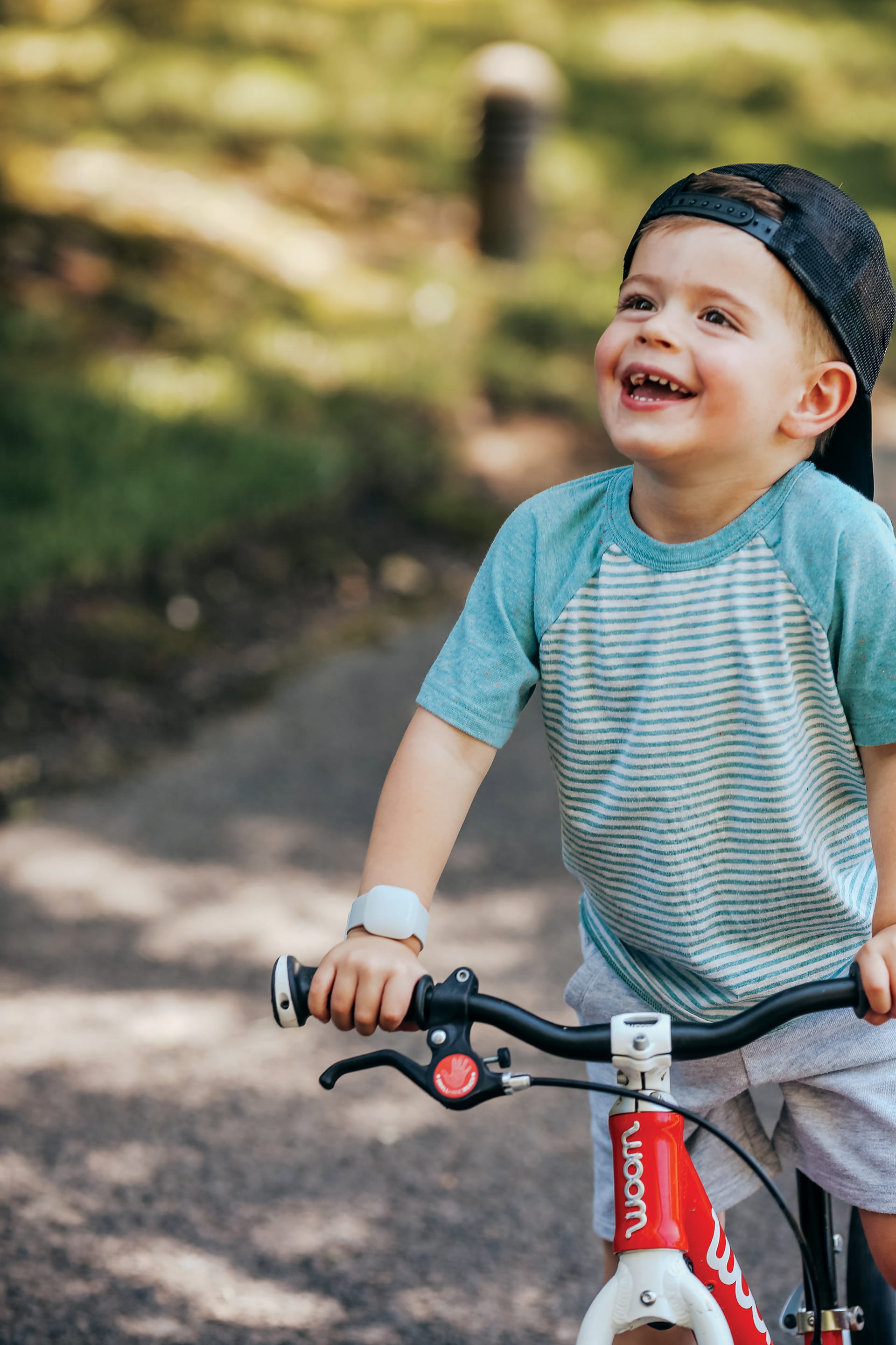 A happy child on a bicycle with the Littlebird CareTracker on their arm 